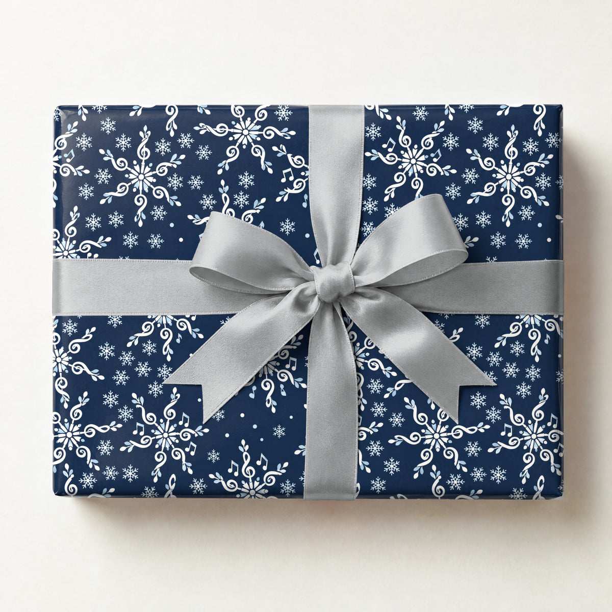 Treble Clef Snowflakes Wrapping Paper, a gift box wrapped in it and tied with a satin ribbon