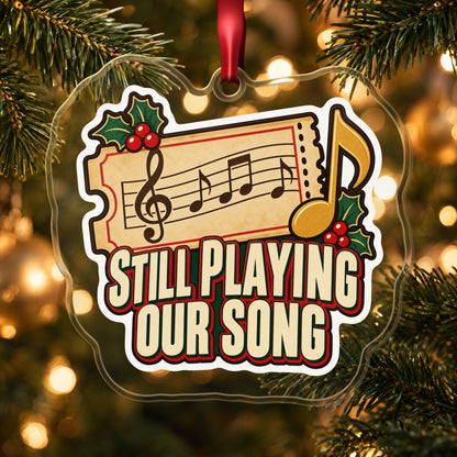 Still Playing Our Song Concert Ticket clear acrylic Christmas ornament hanging on a lit Christmas tree with warm gold lights