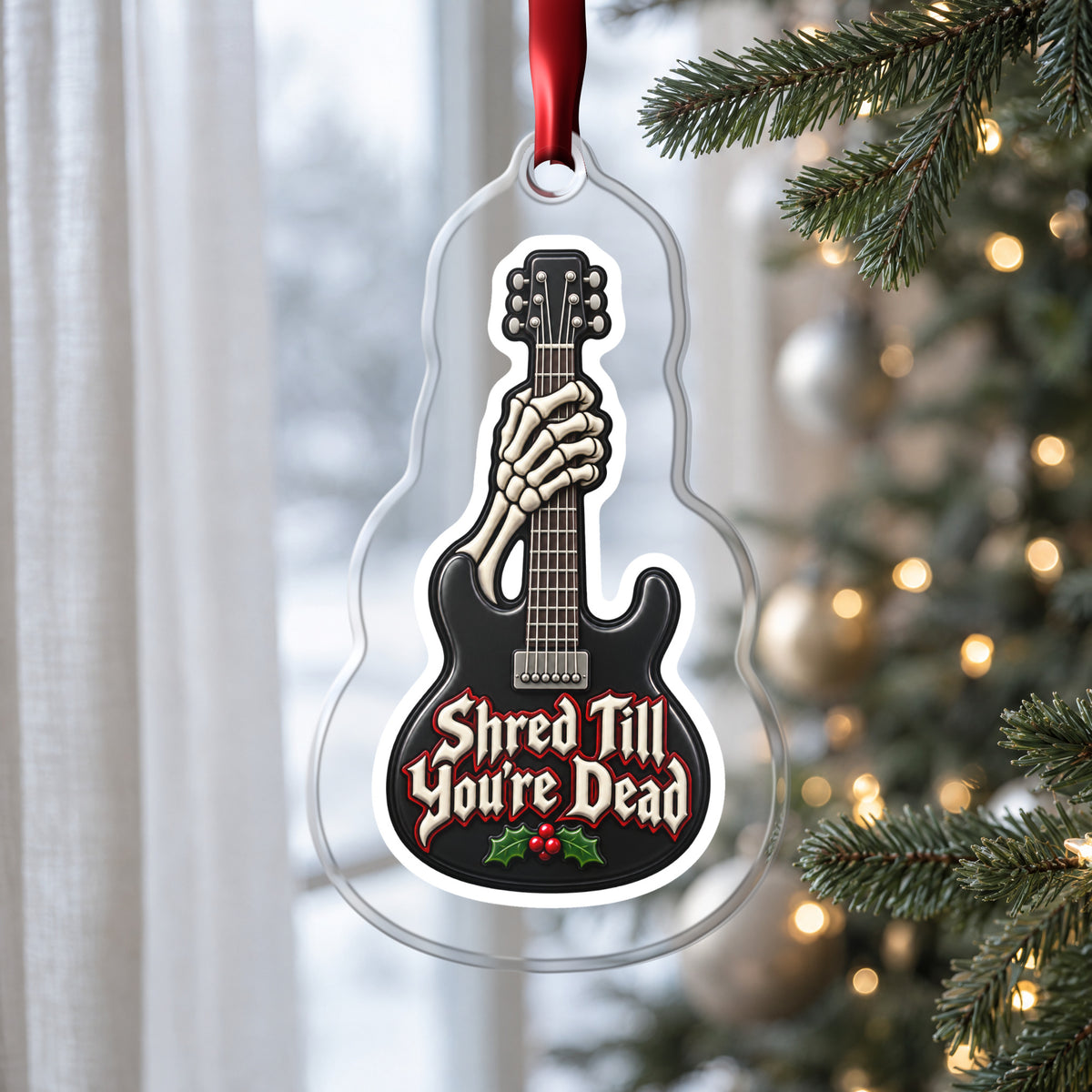 Shred Till You're Dead Skeleton Guitar clear acrylic Christmas ornament hanging on a Christmas tree by a window in soft daylight