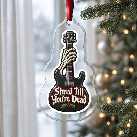 Shred Till You're Dead Skeleton Guitar clear acrylic Christmas ornament hanging on a Christmas tree by a window in soft daylight