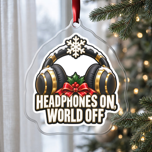 Headphones On, World Off clear acrylic Christmas ornament hanging on a Christmas tree by a window in soft daylight