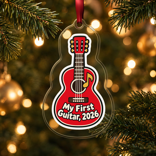 My First Guitar 2026 clear acrylic Christmas ornament hanging on a lit Christmas tree with warm gold lights