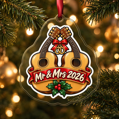 Mr & Mrs First Christmas 2026 Guitar clear acrylic Christmas ornament hanging on a lit Christmas tree with warm gold lights