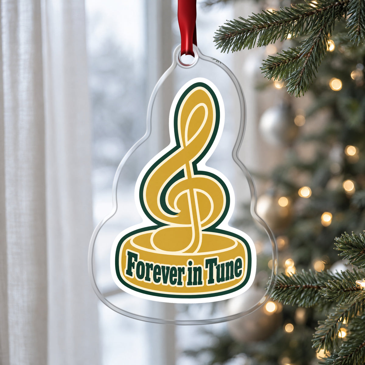 Forever in Tune Treble Clef clear acrylic Christmas ornament hanging on a Christmas tree by a window in soft daylight