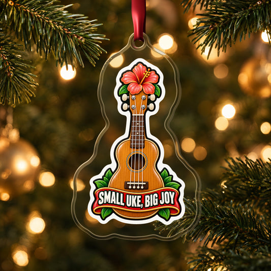 Small Uke, Big Joy Ukulele clear acrylic Christmas ornament hanging on a lit Christmas tree with warm gold lights