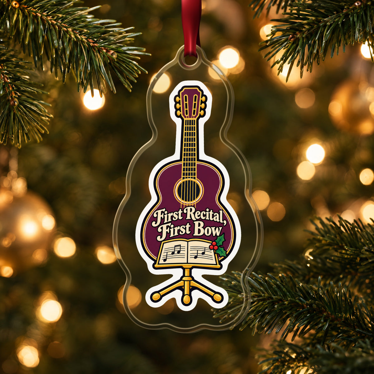 First Recital Acoustic Guitar clear acrylic Christmas ornament hanging on a lit Christmas tree with warm gold lights