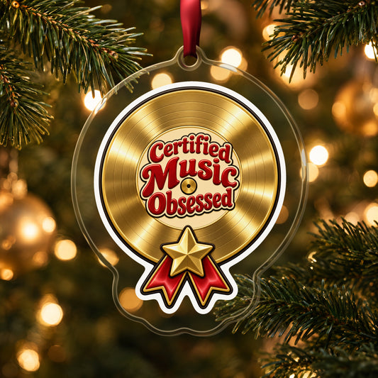 Certified Music Obsessed Gold Record clear acrylic Christmas ornament hanging on a lit Christmas tree with warm gold lights