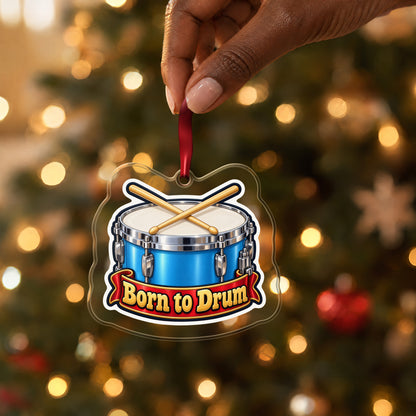 Born to Drum Snare Drum clear acrylic Christmas ornament held by its red ribbon in a hand, shown at its real size