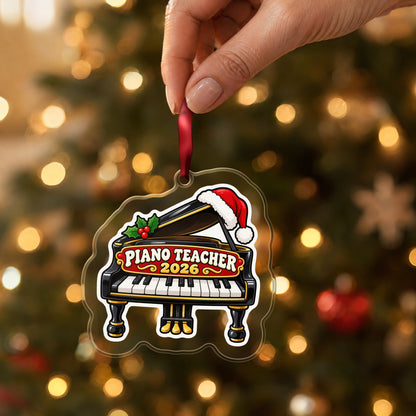 Piano Teacher 2026 clear acrylic Christmas ornament held by its red ribbon in a hand, shown at its real size
