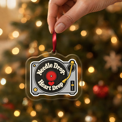 Needle Drop, Heart Drop Turntable clear acrylic Christmas ornament held by its red ribbon in a hand, shown at its real size