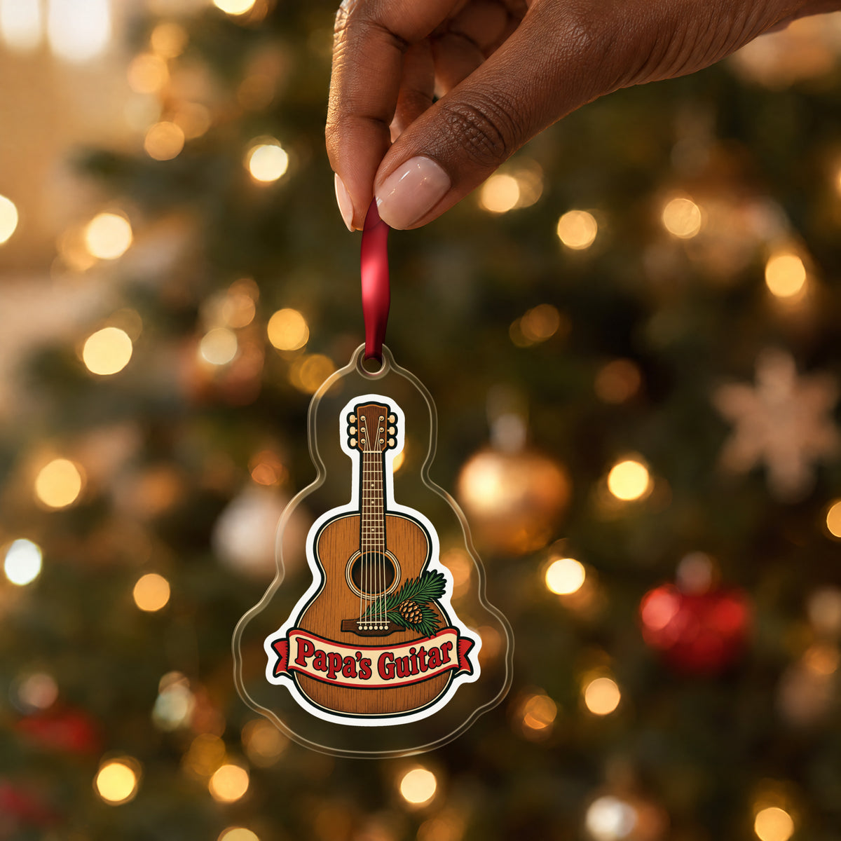 Papa's Guitar Christmas Ornament for Grandpa clear acrylic Christmas ornament held by its red ribbon in a hand, shown at its real size