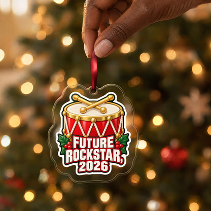 Future Rockstar 2026 Toy Drum clear acrylic Christmas ornament held by its red ribbon in a hand, shown at its real size
