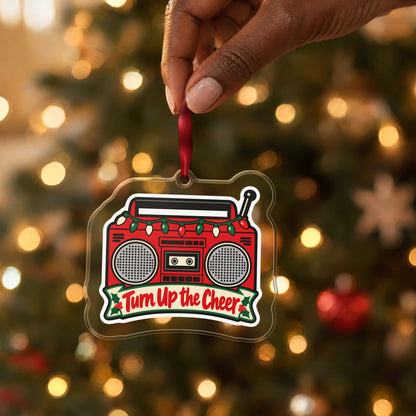 Turn Up the Cheer Boombox clear acrylic Christmas ornament held by its red ribbon in a hand, shown at its real size