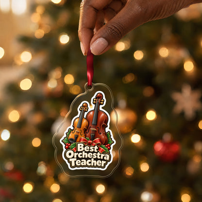 Best Orchestra Teacher clear acrylic Christmas ornament held by its red ribbon in a hand, shown at its real size