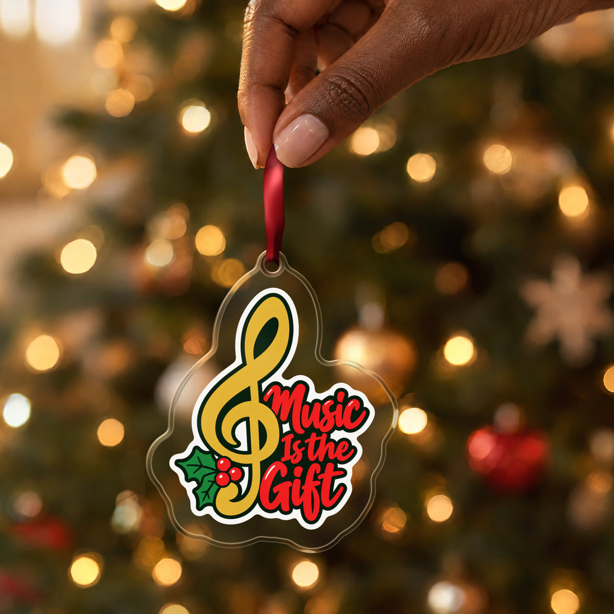 Music Is the Gift Treble Clef clear acrylic Christmas ornament held by its red ribbon in a hand, shown at its real size