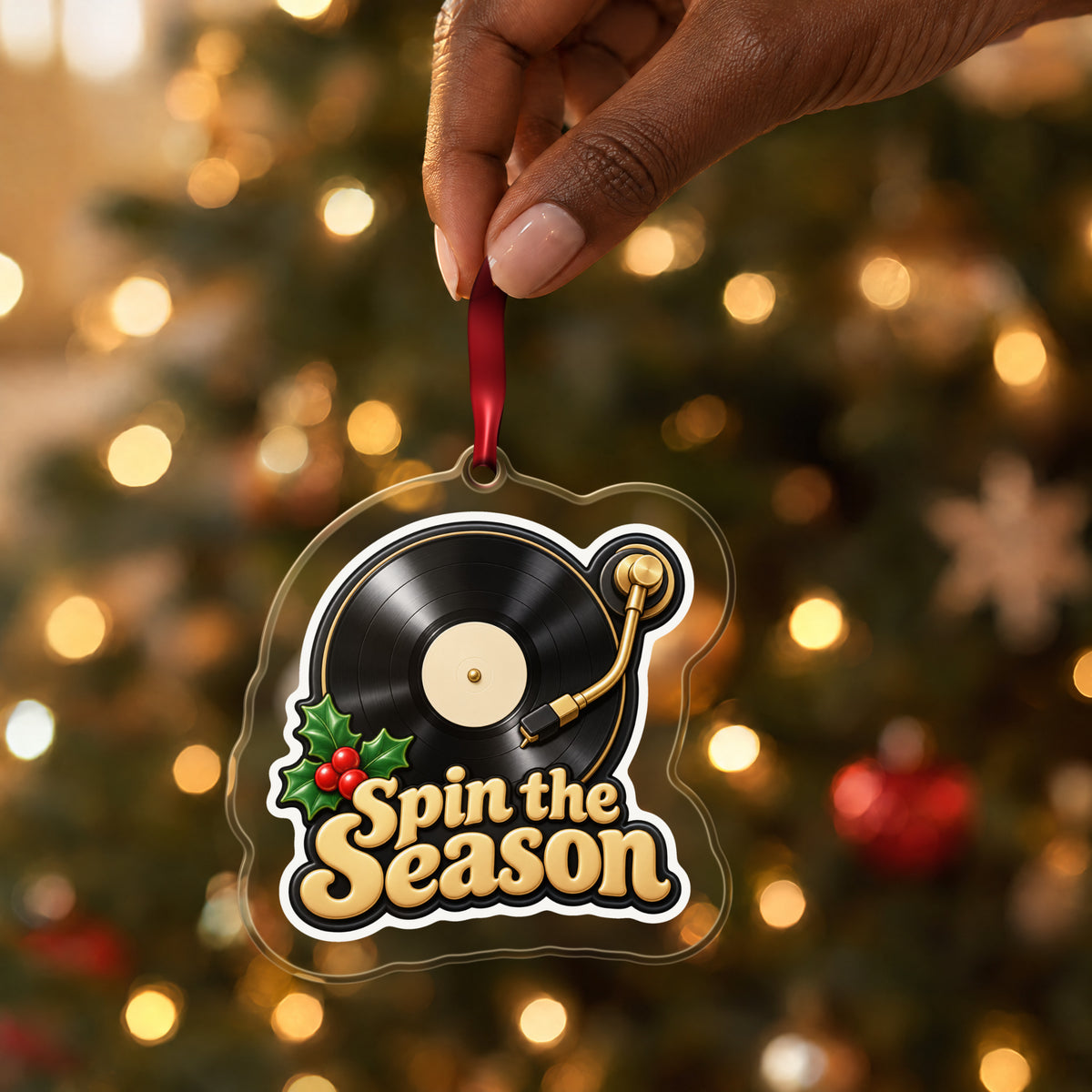 Spin the Season Vinyl Record clear acrylic Christmas ornament held by its red ribbon in a hand, shown at its real size