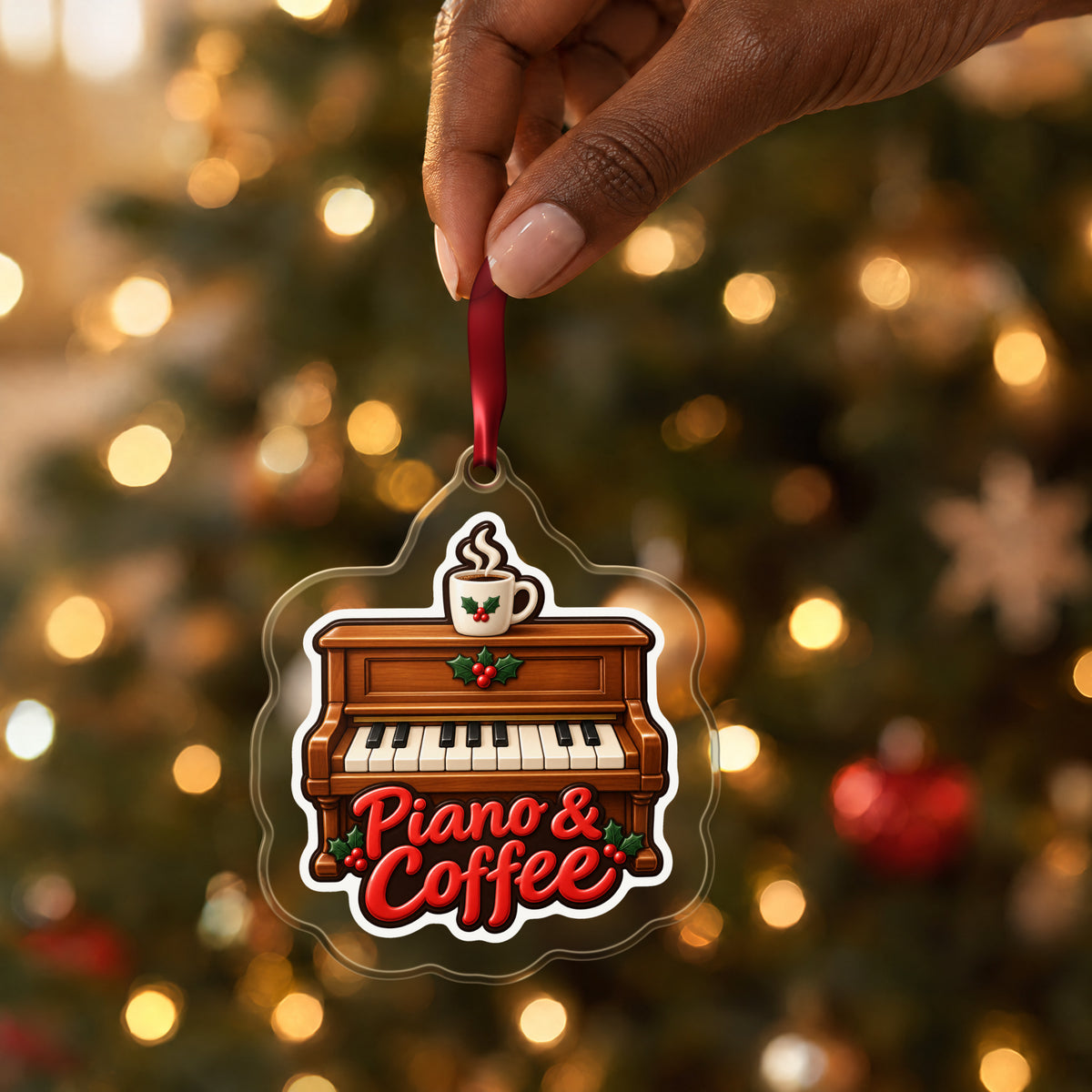 Piano & Coffee Christmas Ornament for Pianists clear acrylic Christmas ornament held by its red ribbon in a hand, shown at its real size