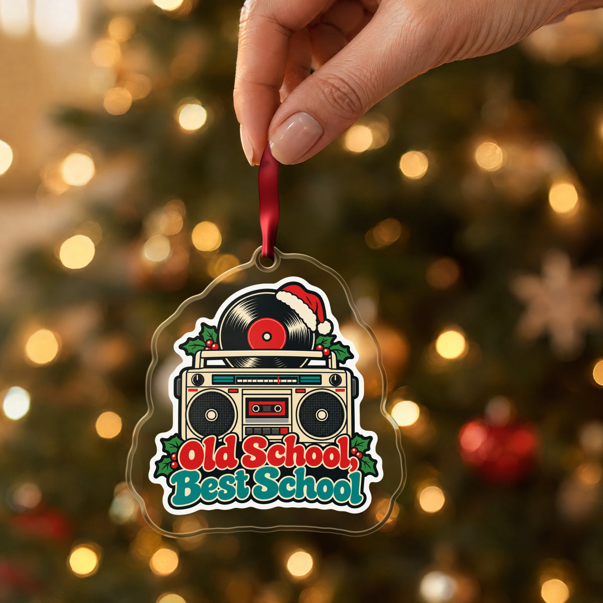 Old School, Best School Boombox clear acrylic Christmas ornament held by its red ribbon in a hand, shown at its real size