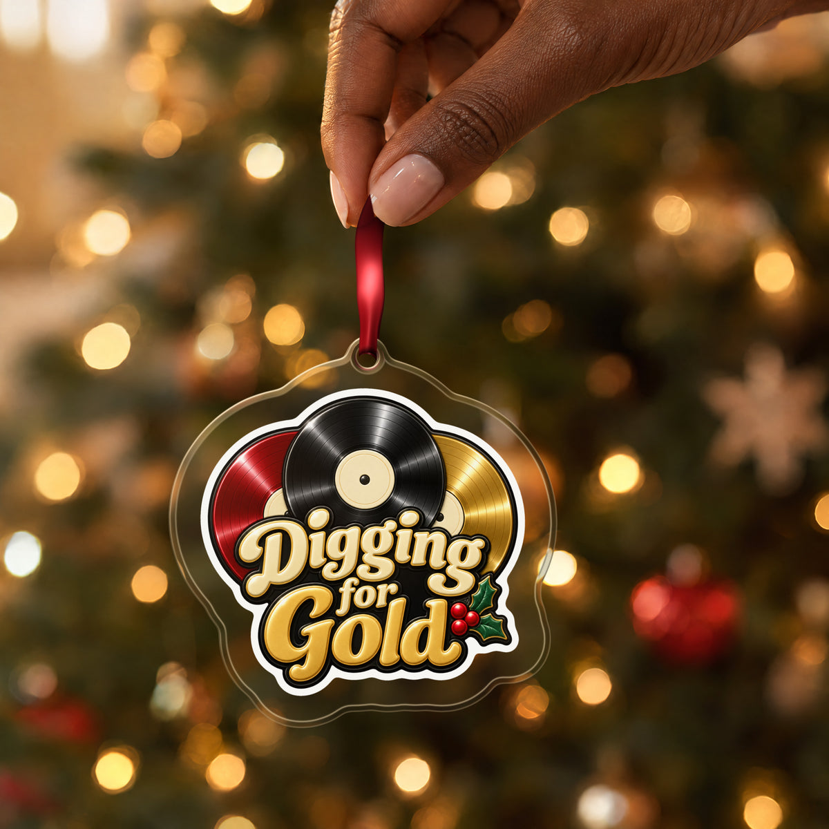 Digging for Gold Vinyl Records clear acrylic Christmas ornament held by its red ribbon in a hand, shown at its real size