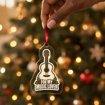 For My Music Lover Acoustic Guitar clear acrylic Christmas ornament held by its red ribbon in a hand, shown at its real size