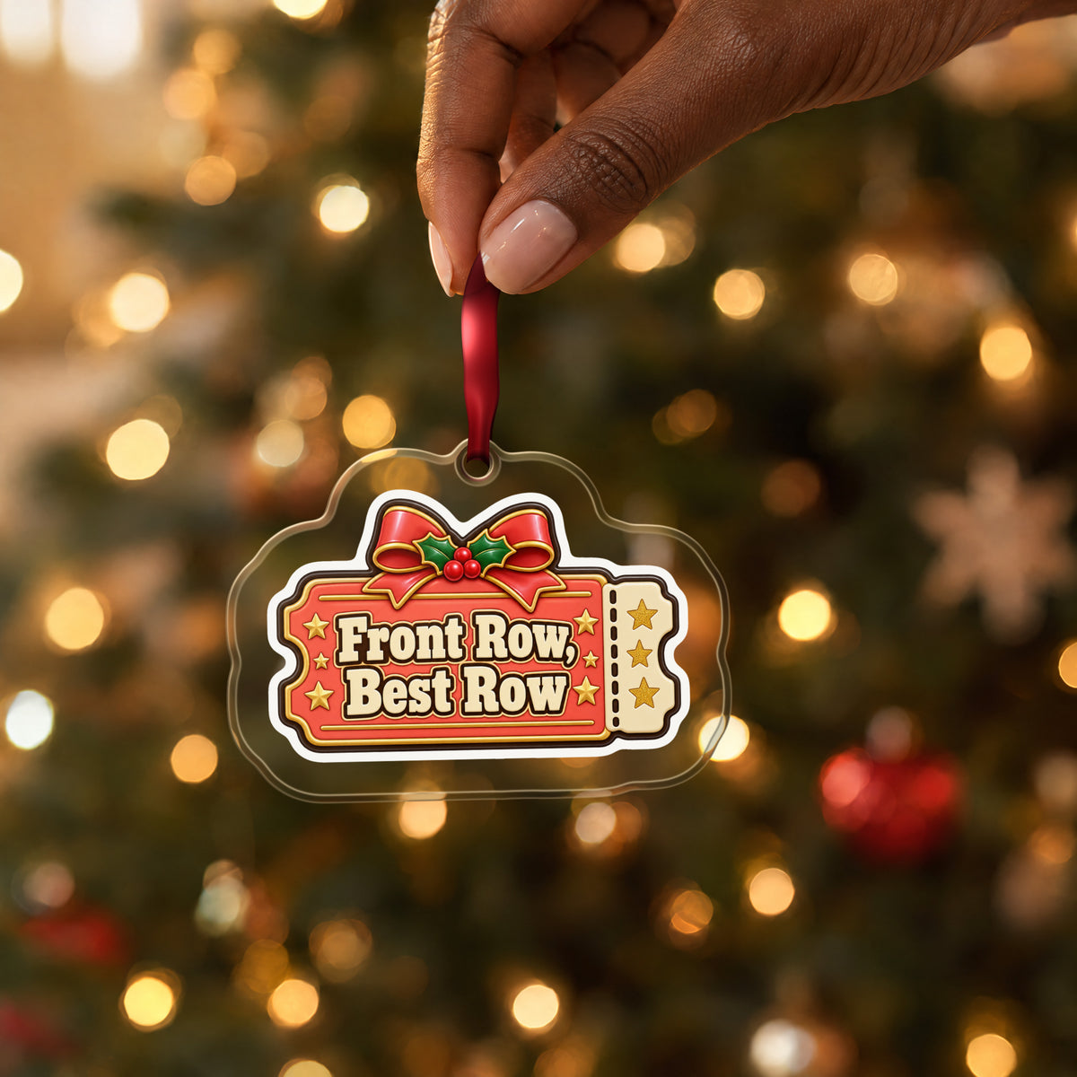 Front Row, Best Row Concert Ticket clear acrylic Christmas ornament held by its red ribbon in a hand, shown at its real size