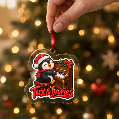 Tux & Ivories Penguin Piano clear acrylic Christmas ornament held by its red ribbon in a hand, shown at its real size