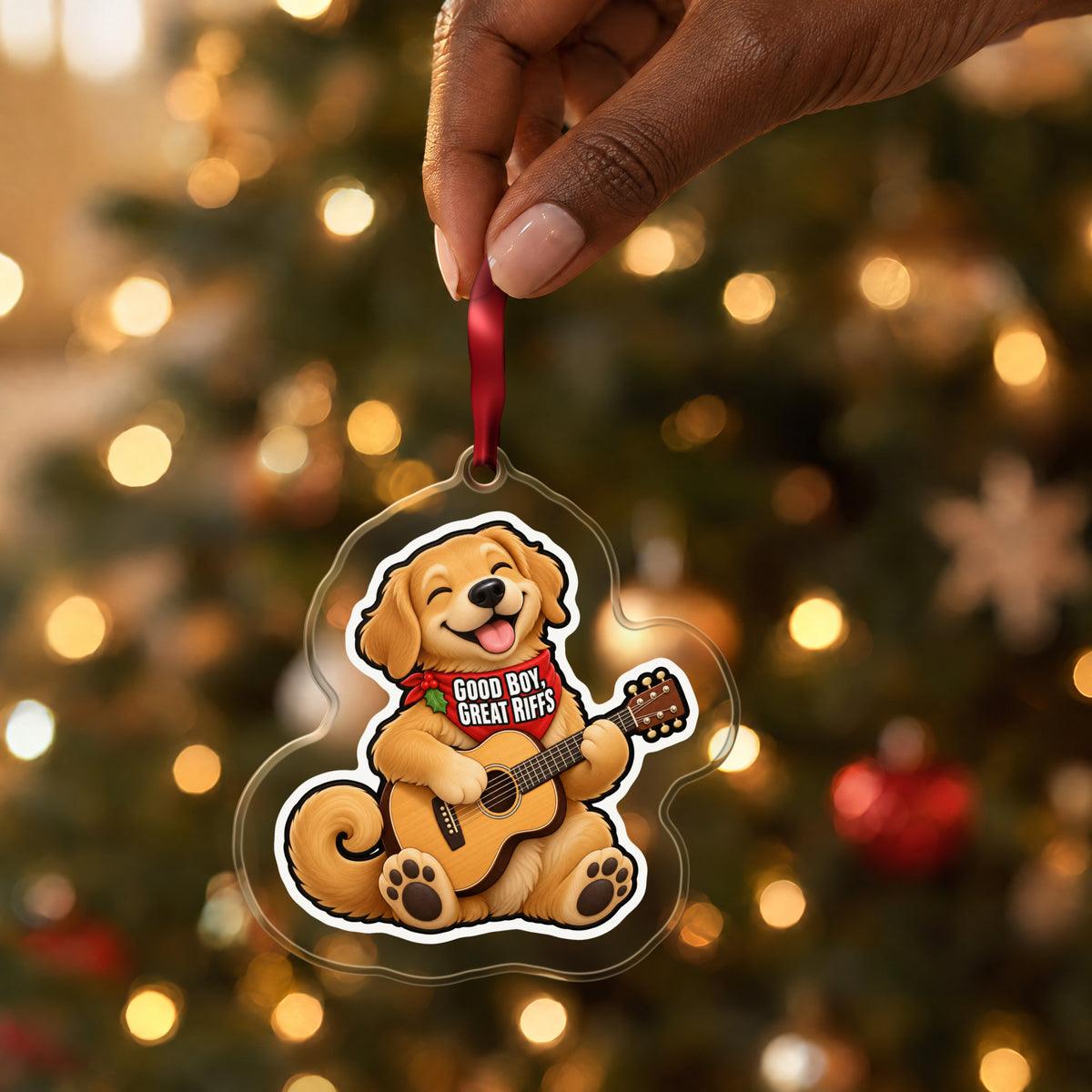 Good Boy, Great Riffs Dog Guitar clear acrylic Christmas ornament held by its red ribbon in a hand, shown at its real size