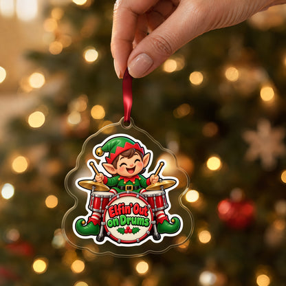 Elfin' Out on Drums Elf Drummer clear acrylic Christmas ornament held by its red ribbon in a hand, shown at its real size