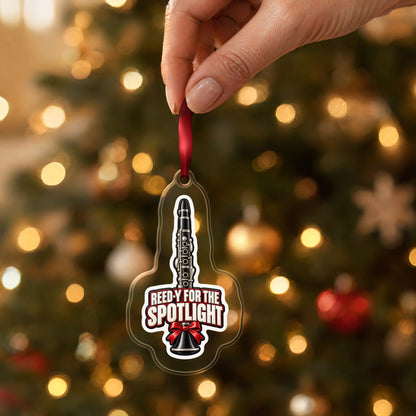 Reed-y for the Spotlight Clarinet clear acrylic Christmas ornament held by its red ribbon in a hand, shown at its real size