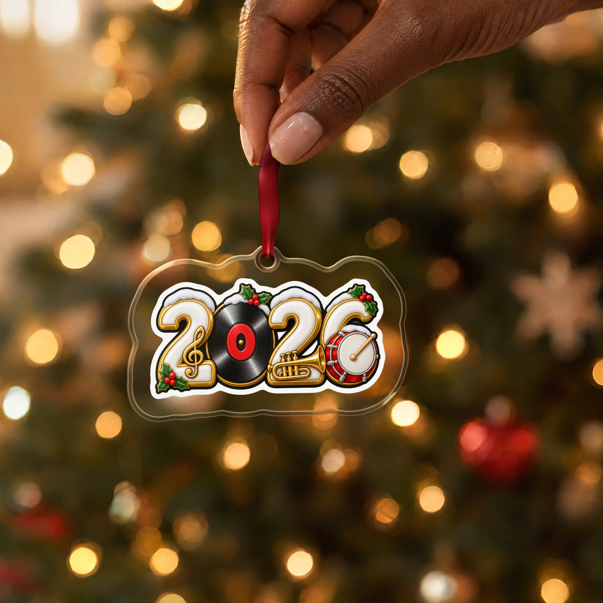 2026 Music Lover clear acrylic Christmas ornament held by its red ribbon in a hand, shown at its real size