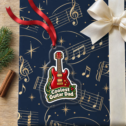 Coolest Guitar Dad clear acrylic Christmas ornament lying on a gift wrapped in Rhythm and Beat music wrapping paper