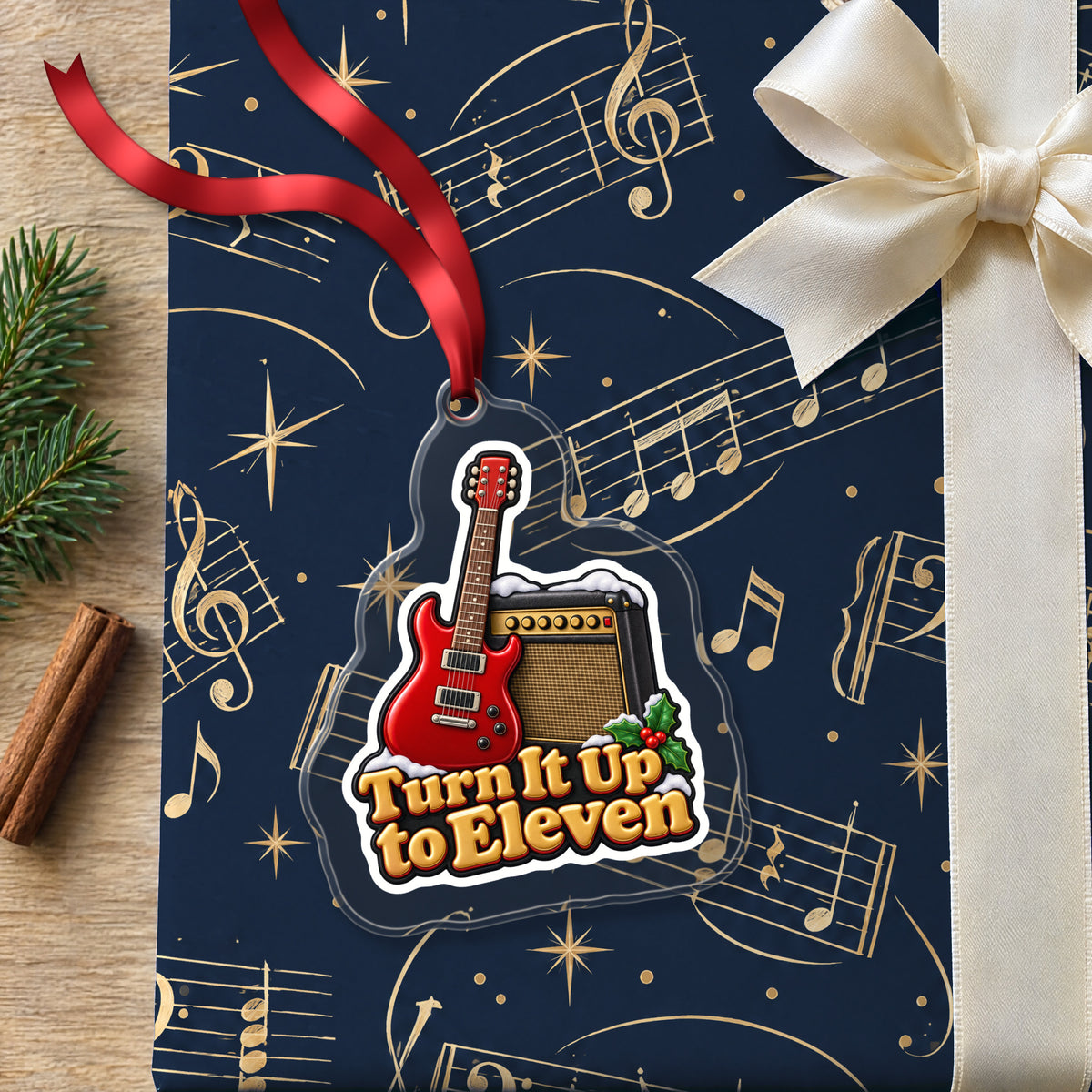 Turn It Up to Eleven Guitar and Amp clear acrylic Christmas ornament lying on a gift wrapped in Rhythm and Beat music wrapping paper