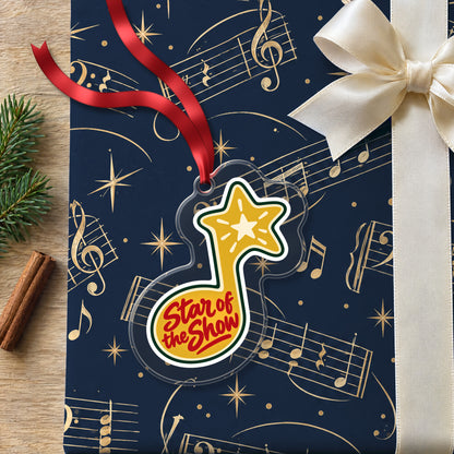 Star of the Show Music Note clear acrylic Christmas ornament lying on a gift wrapped in Rhythm and Beat music wrapping paper