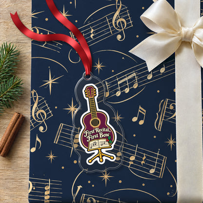 First Recital Acoustic Guitar clear acrylic Christmas ornament lying on a gift wrapped in Rhythm and Beat music wrapping paper