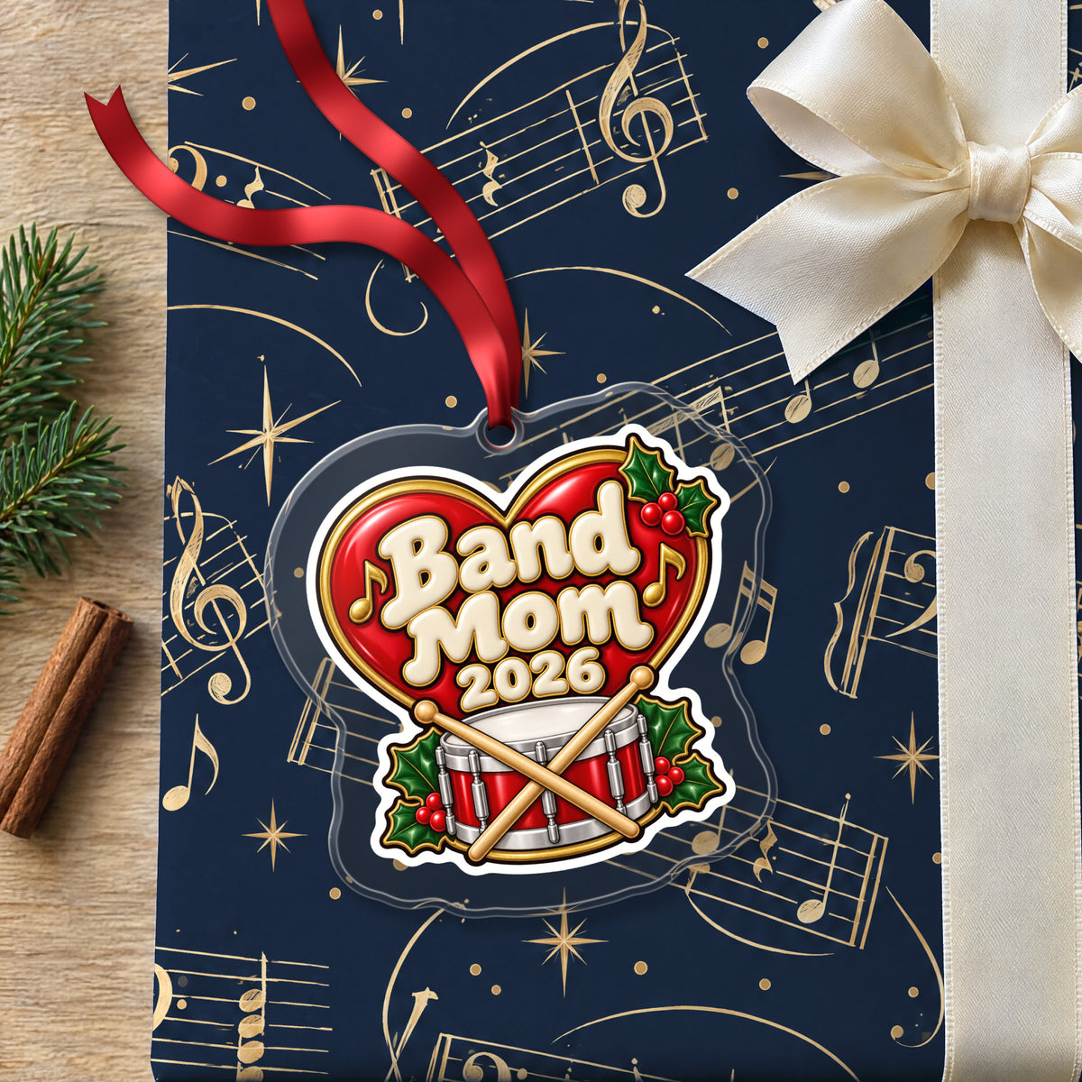Band Mom 2026 clear acrylic Christmas ornament lying on a gift wrapped in Rhythm and Beat music wrapping paper