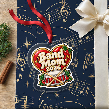 Band Mom 2026 clear acrylic Christmas ornament lying on a gift wrapped in Rhythm and Beat music wrapping paper