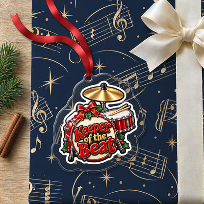 Keeper of the Beat Drum Kit clear acrylic Christmas ornament lying on a gift wrapped in Rhythm and Beat music wrapping paper