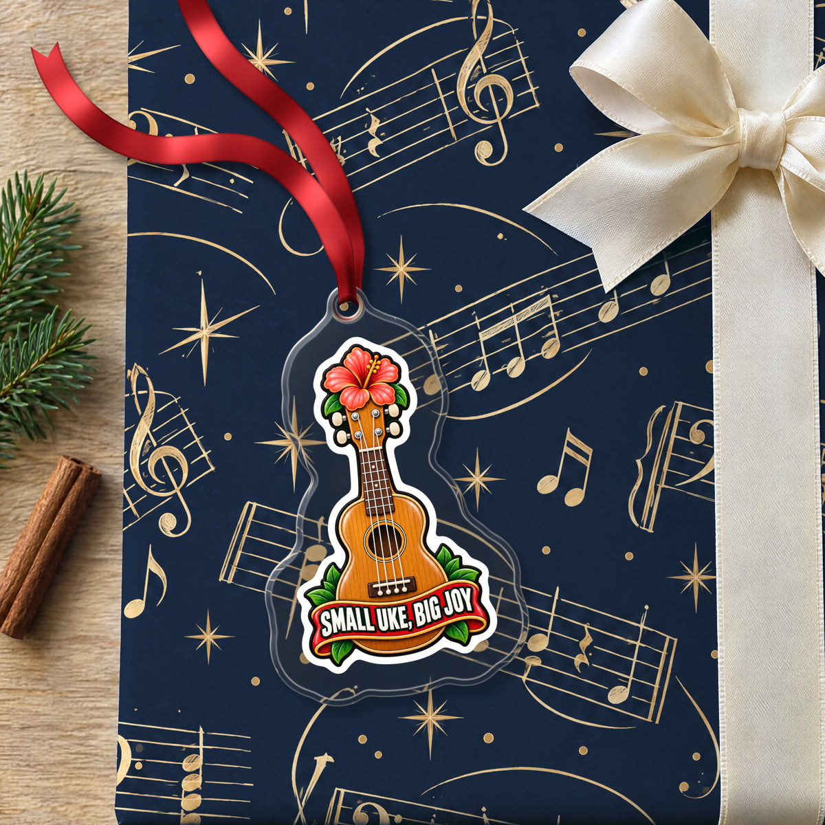 Small Uke, Big Joy Ukulele clear acrylic Christmas ornament lying on a gift wrapped in Rhythm and Beat music wrapping paper