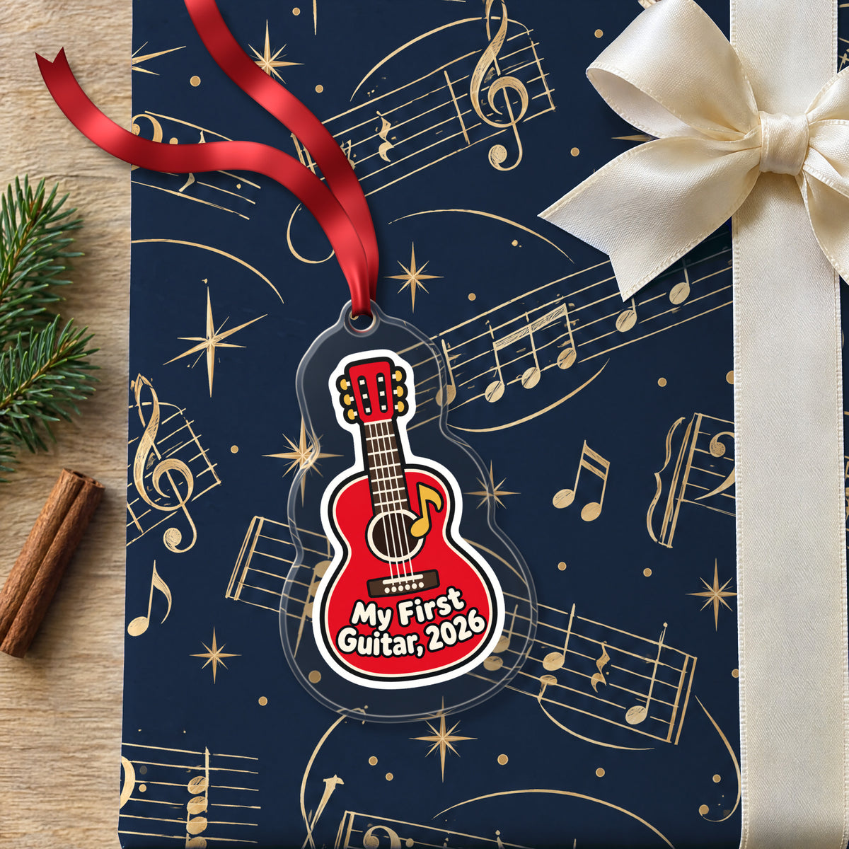 My First Guitar 2026 clear acrylic Christmas ornament lying on a gift wrapped in Rhythm and Beat music wrapping paper