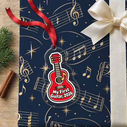 My First Guitar 2026 clear acrylic Christmas ornament lying on a gift wrapped in Rhythm and Beat music wrapping paper