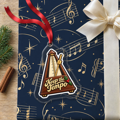 Keep the Tempo Metronome clear acrylic Christmas ornament lying on a gift wrapped in Rhythm and Beat music wrapping paper