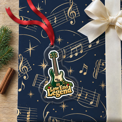 Low End Legend Bass Guitar clear acrylic Christmas ornament lying on a gift wrapped in Rhythm and Beat music wrapping paper