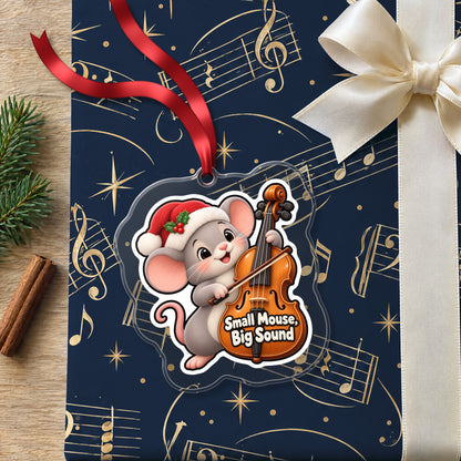 Small Mouse, Big Sound Cello clear acrylic Christmas ornament lying on a gift wrapped in Rhythm and Beat music wrapping paper