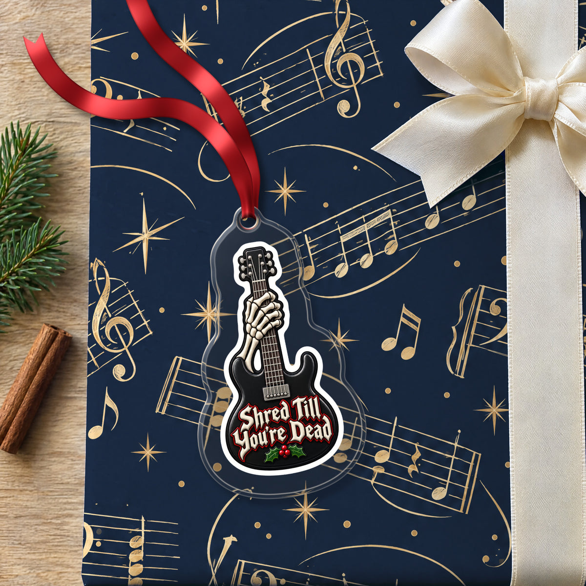 Shred Till You're Dead Skeleton Guitar clear acrylic Christmas ornament lying on a gift wrapped in Rhythm and Beat music wrapping paper