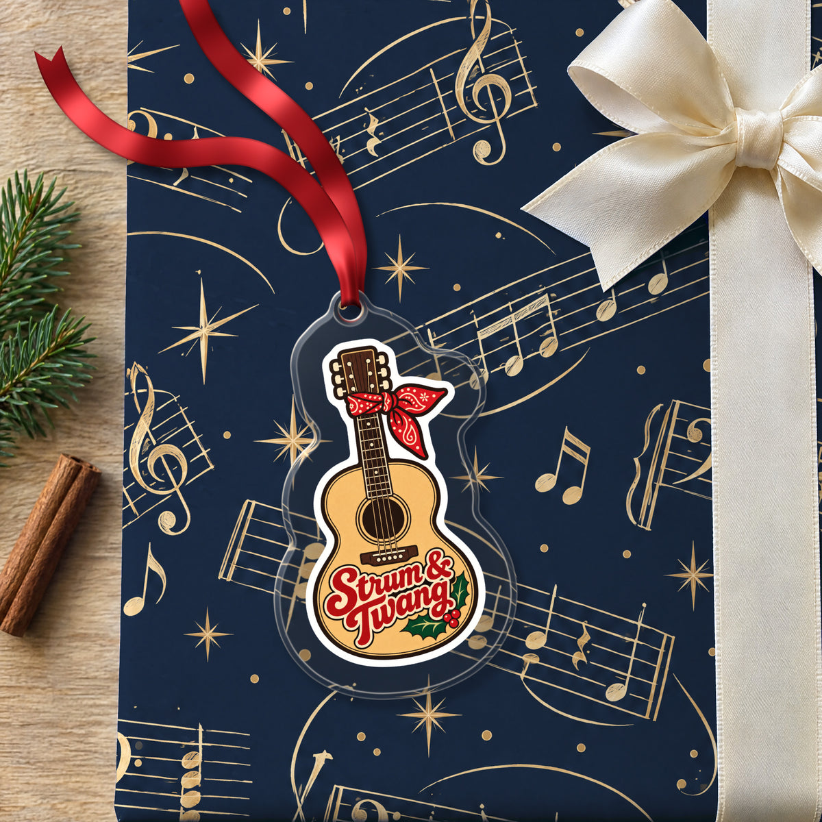 Strum & Twang Country Guitar clear acrylic Christmas ornament lying on a gift wrapped in Rhythm and Beat music wrapping paper