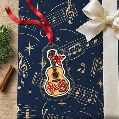 Strum & Twang Country Guitar clear acrylic Christmas ornament lying on a gift wrapped in Rhythm and Beat music wrapping paper