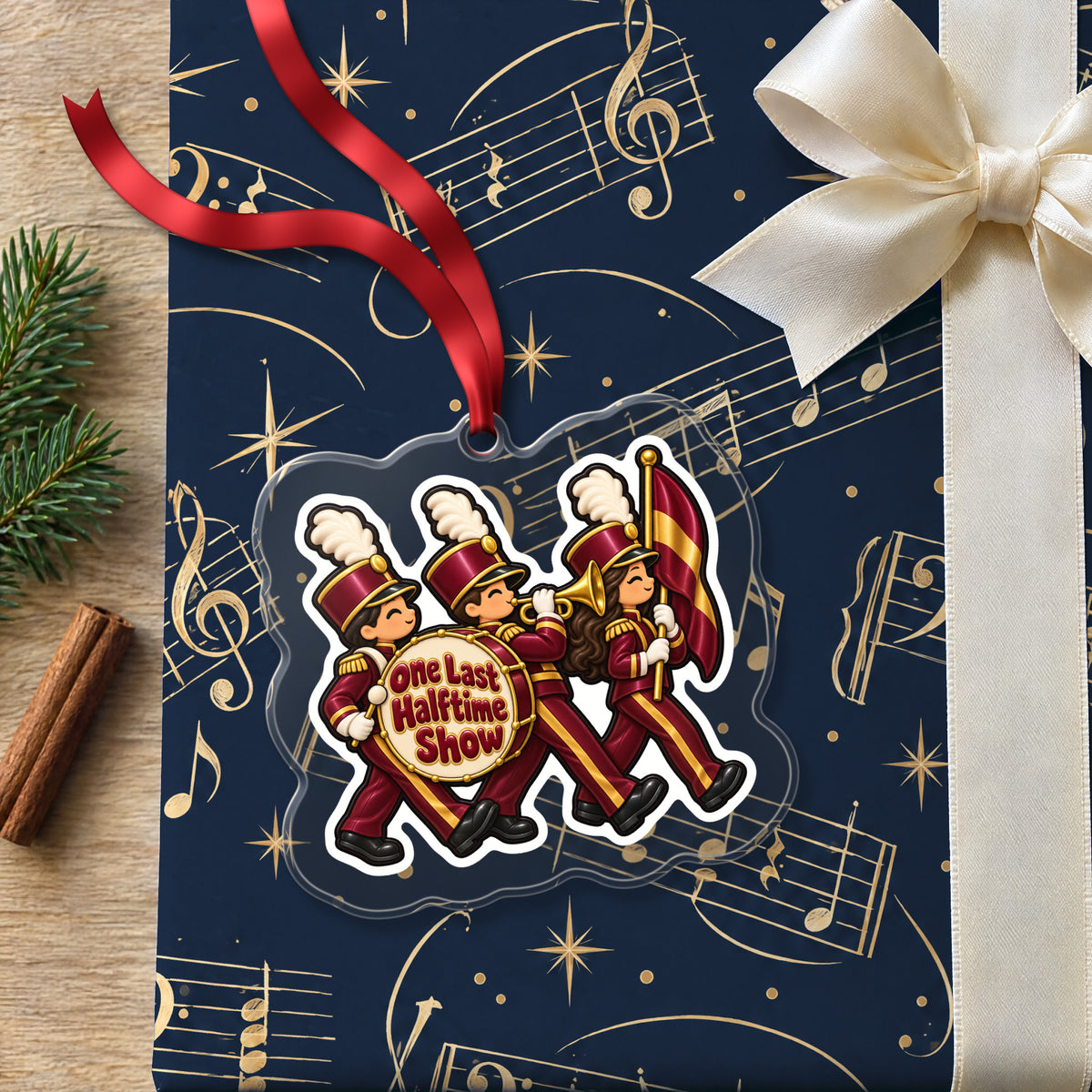 One Last Halftime Show Marching Band clear acrylic Christmas ornament lying on a gift wrapped in Rhythm and Beat music wrapping paper