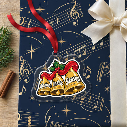 Ringing In the Season Handbells clear acrylic Christmas ornament lying on a gift wrapped in Rhythm and Beat music wrapping paper