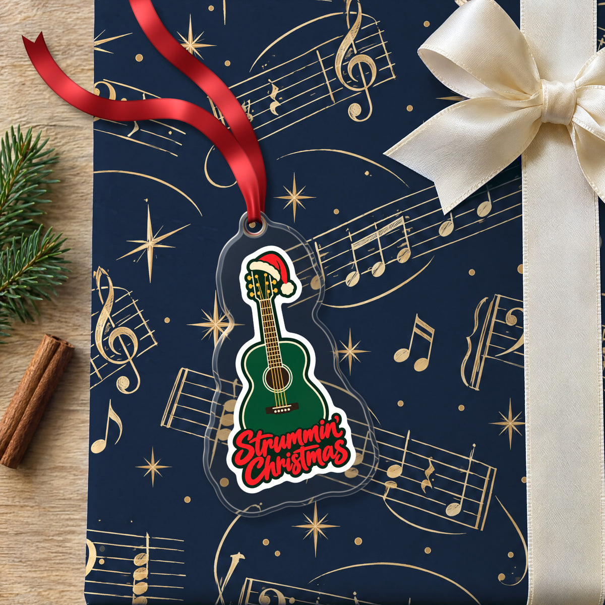 Strummin' Christmas Acoustic Guitar clear acrylic Christmas ornament lying on a gift wrapped in Rhythm and Beat music wrapping paper