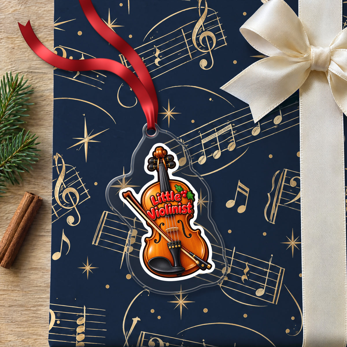 Little Violinist clear acrylic Christmas ornament lying on a gift wrapped in Rhythm and Beat music wrapping paper